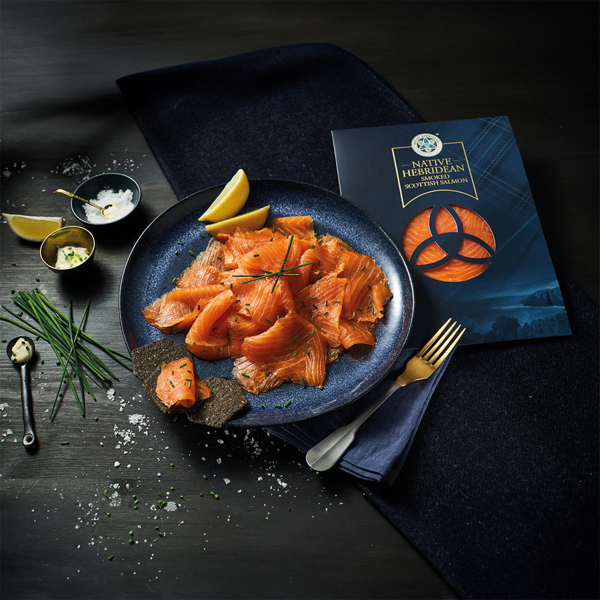 Native Hebridean Scottish smoked salmon served with lemon and herbs beside its branded packaging