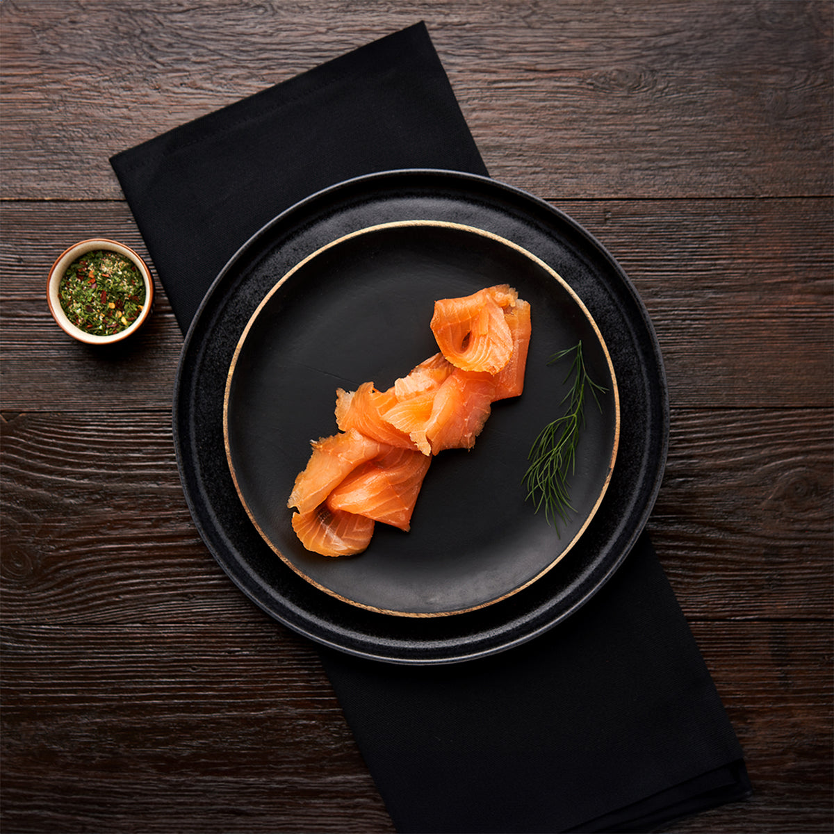 Slices of Native Hebridean Scottish smoked salmon arranged on a black plate with dill